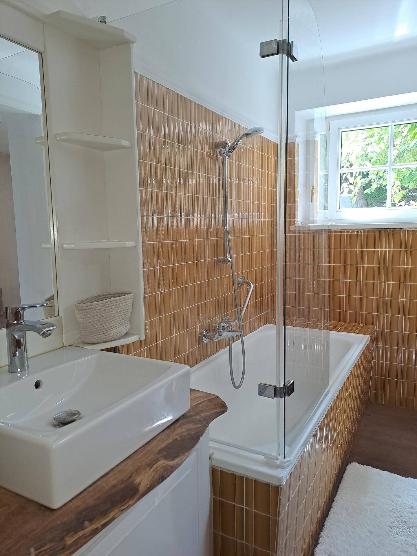 Modernes Badezimmer mit Badewanne, Duschfunktion und Fenster für angenehmes Tageslicht.