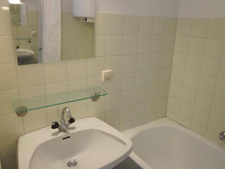 Helles Badezimmer mit Badewanne, Waschbecken und Spiegelschrank, die Wände sind mit hellen Fliesen versehen.