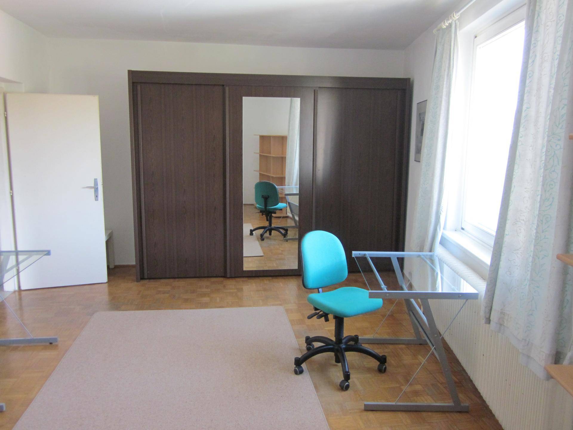 Geräumiges Schlafzimmer mit großem Kleiderschrank, Schreibtisch und viel Tageslicht, bietet Platz zum Wohnen und Arbeiten.