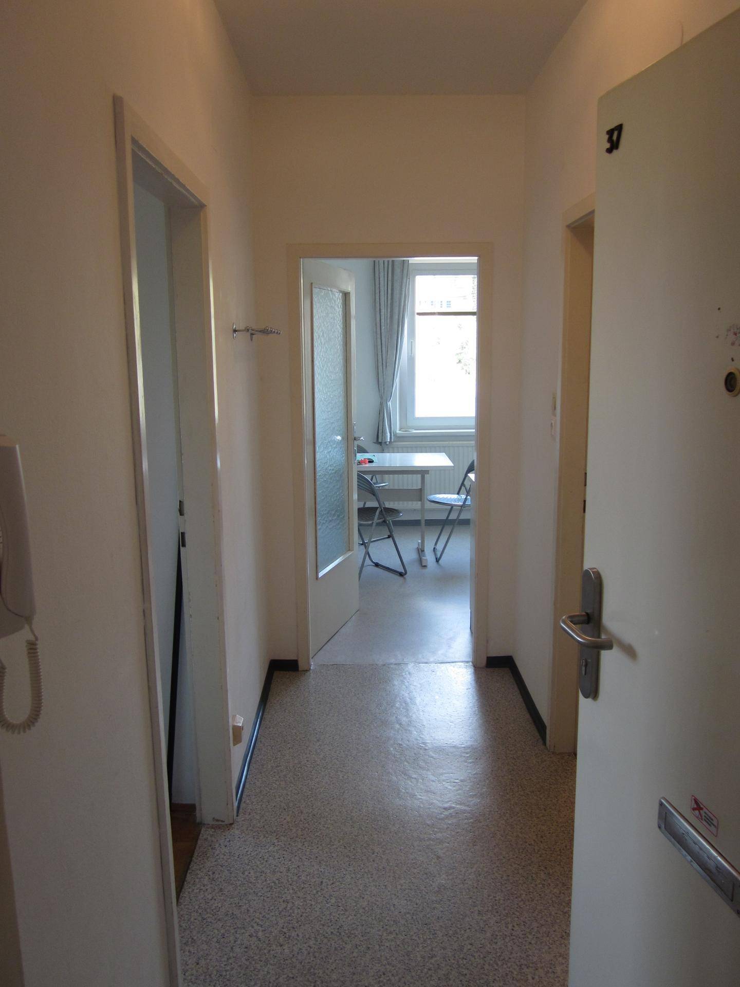 Heller Flur mit Zugang zu verschiedenen Räumen, ausgestattet mit strapazierfähigem Fliesenboden und Gegensprechanlage.