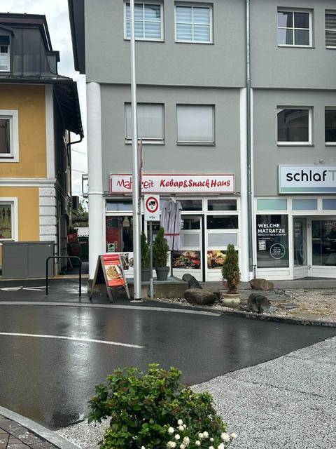 Ansicht eines grauen Gebäudes mit einem Kebab- und Snack-Haus im Erdgeschoss und Wohnungen darüber.