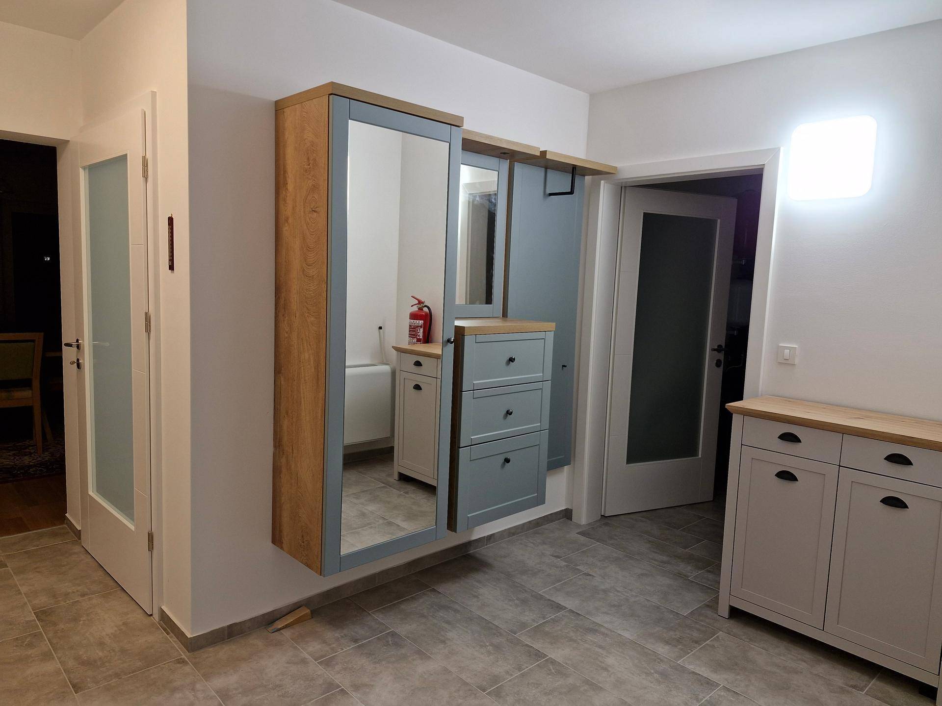 Moderner Eingangsbereich mit Fliesenboden, Spiegelschrank und praktischen Aufbewahrungsmöbeln.