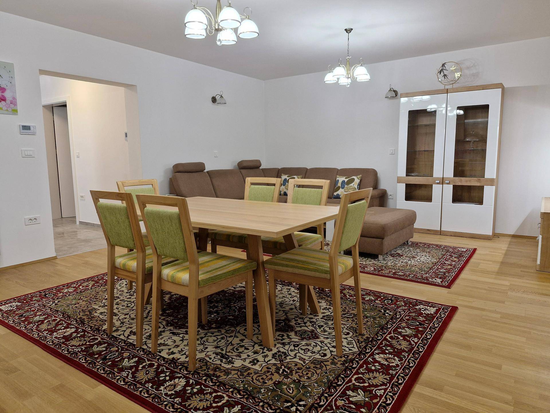 Heller Wohn-Essbereich mit Holzboden, großem Esstisch und gemütlicher Sofaecke.
