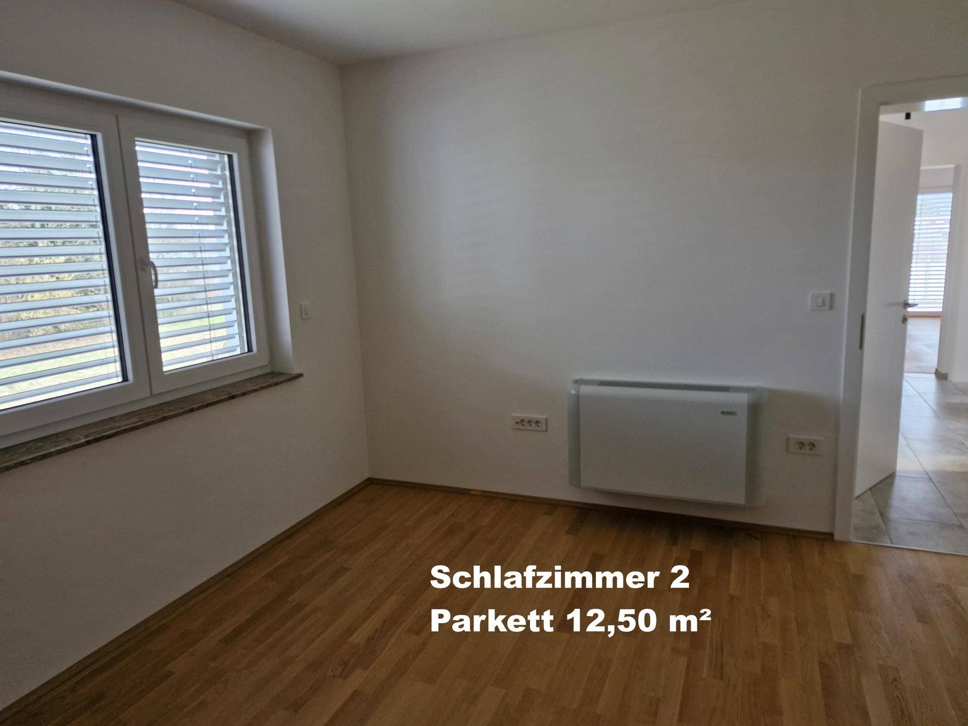 Zweites Schlafzimmer mit Parkettboden und Fenster, ideal für Gäste oder Kinderzimmer.