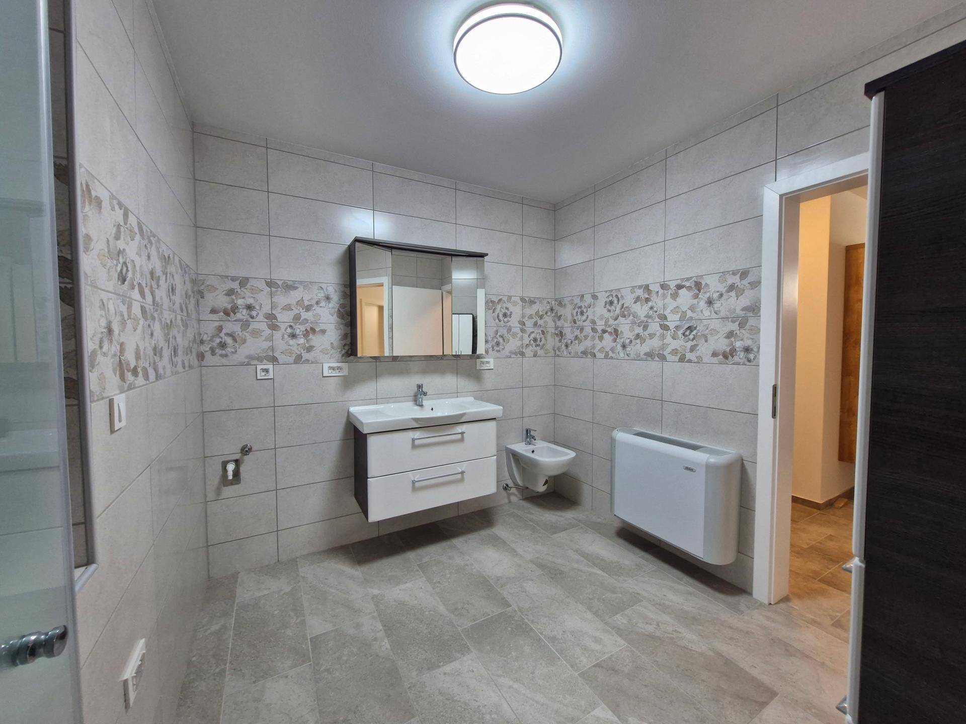 Modernes Badezimmer mit Fliesenboden, Waschtisch, Spiegelschrank und Bidet.