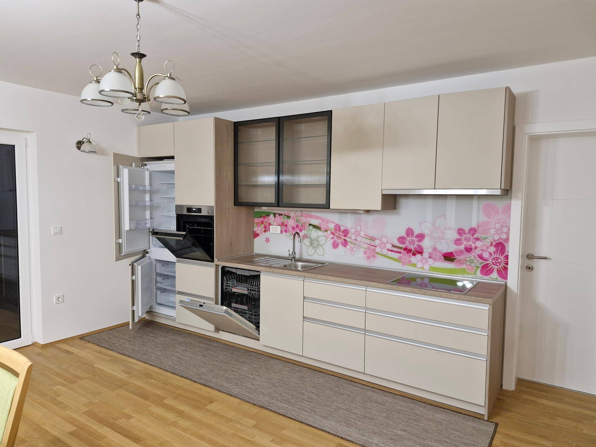 Moderne Einbauküche mit beigen Fronten, integrierten Geräten und einer auffälligen floralen Rückwand.