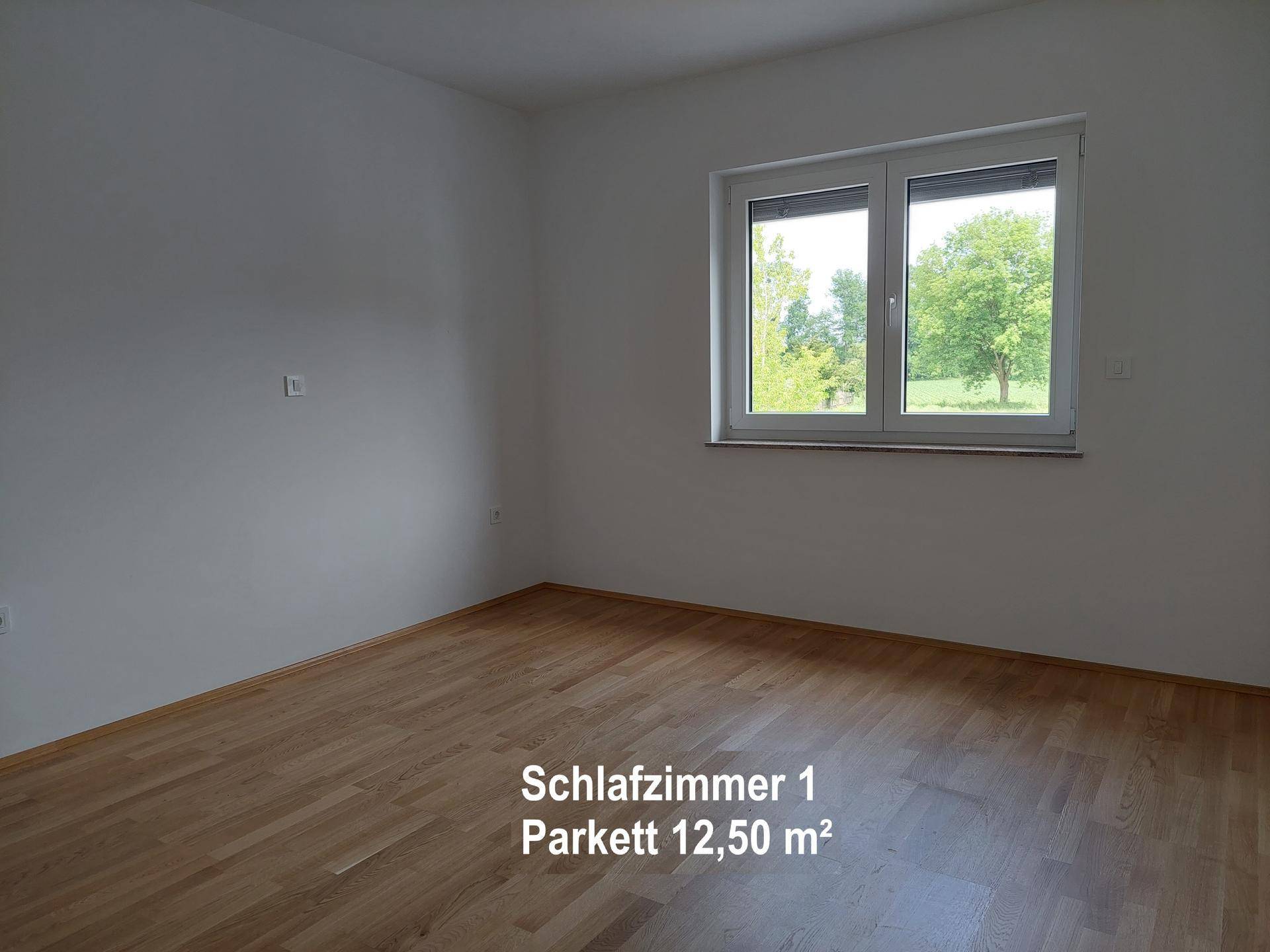 Helles Schlafzimmer mit Parkettboden und großem Fenster, bereit zur individuellen Einrichtung.