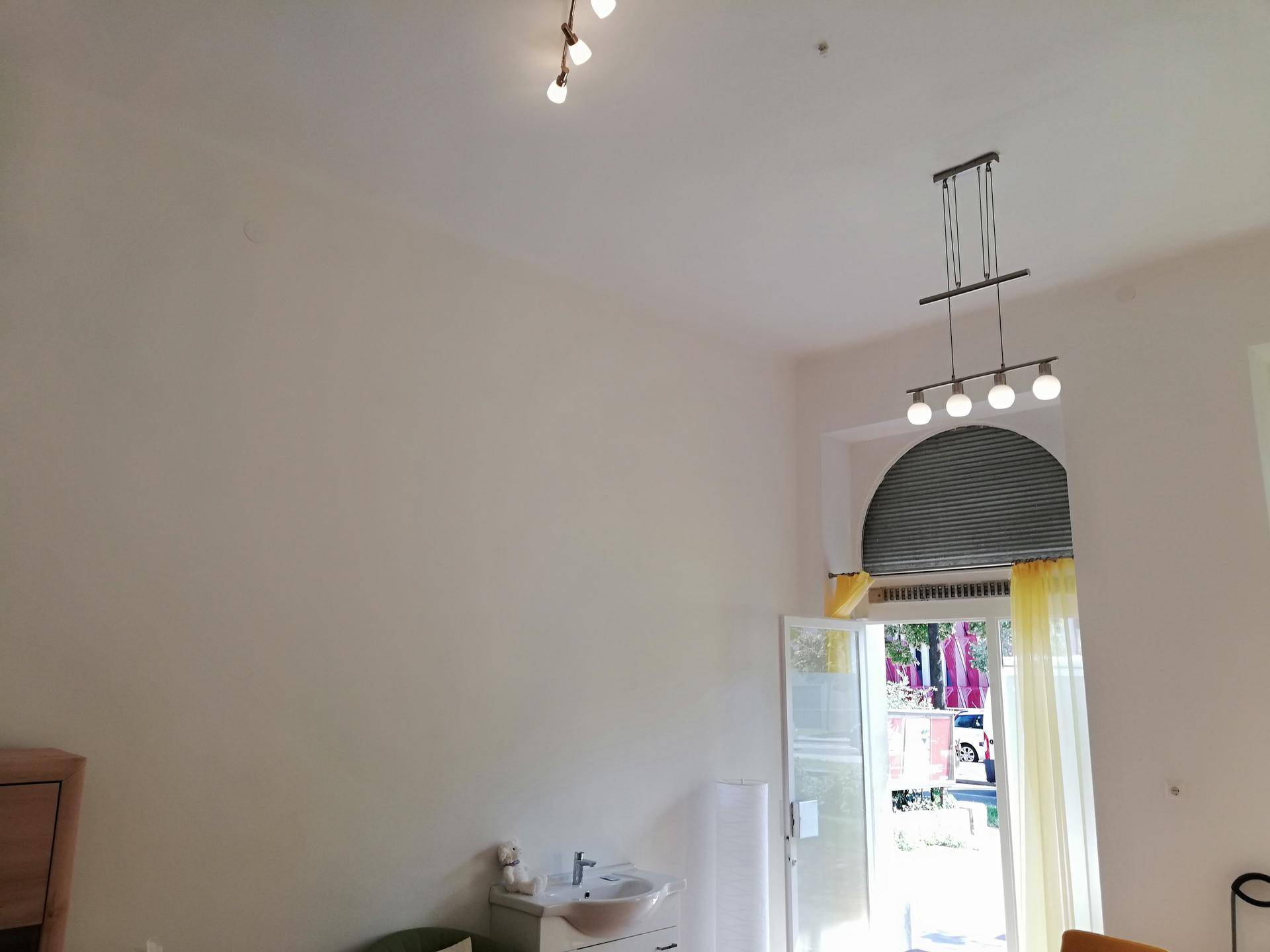 Hohe Decke mit modernen Leuchten über einem Raum mit Waschbecken und einem Fenster mit Bogen.