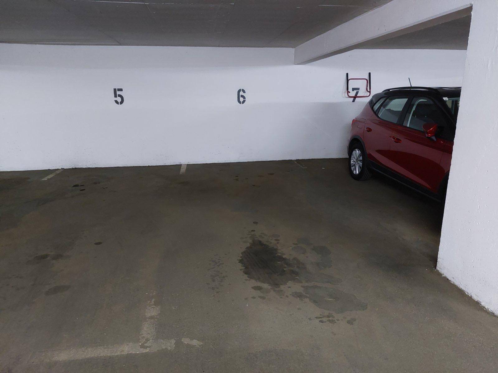 Leerer Stellplatz in der Tiefgarage mit Betonboden und nummerierten Parkplätzen.