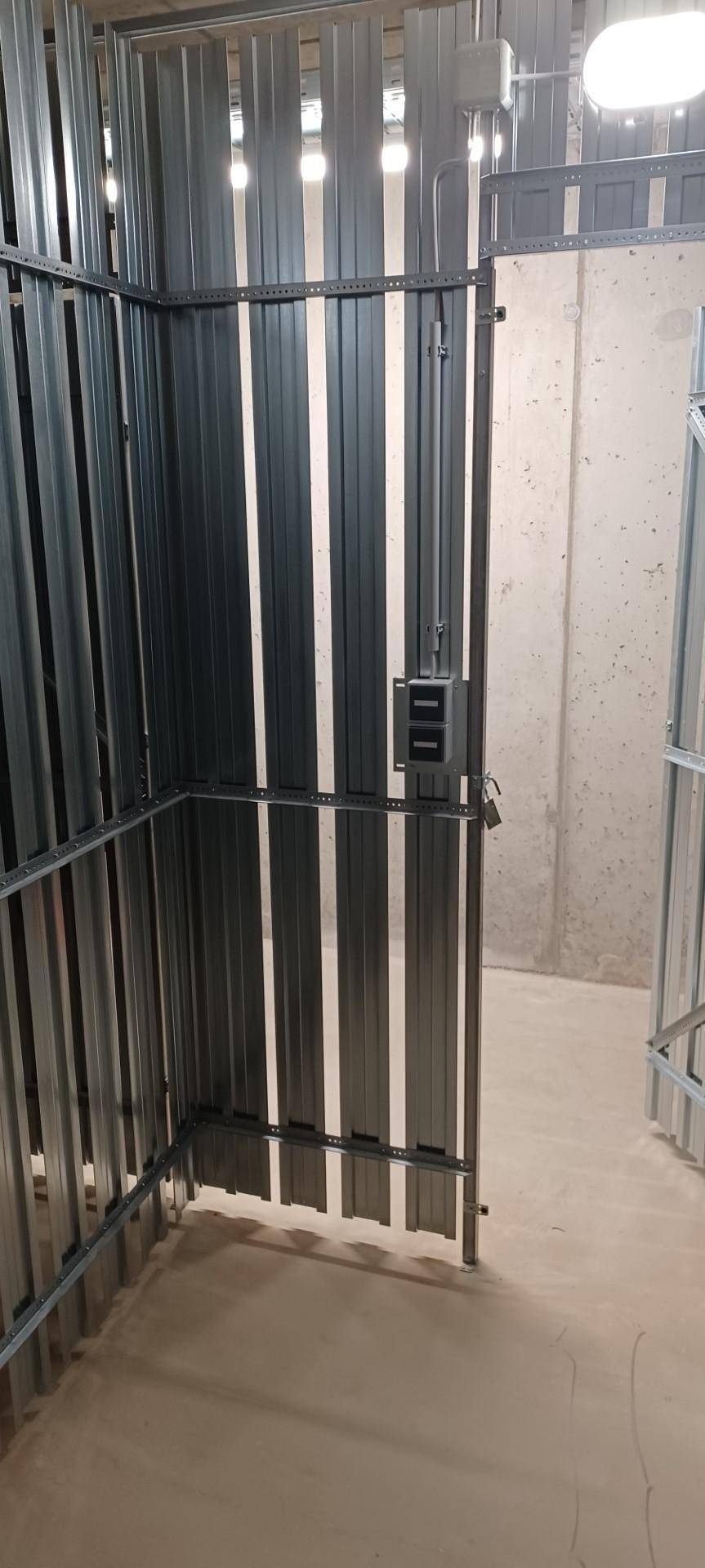 Praktischer Abstellraum im Keller mit Metallabtrennungen und Betonboden für zusätzlichen Stauraum.