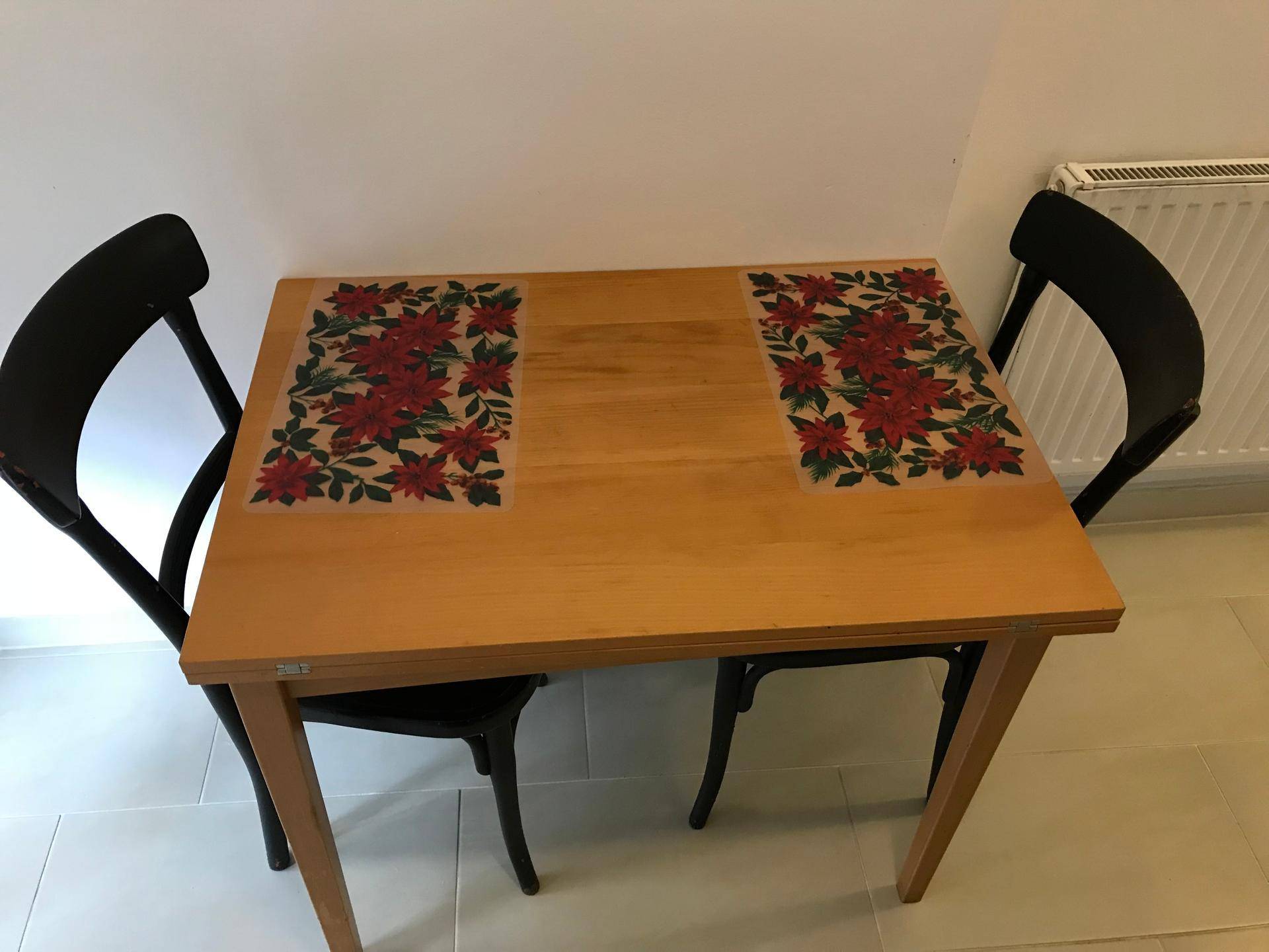 Kleiner Essbereich mit Holztisch und zwei schwarzen Stühlen, perfekt für intime Mahlzeiten.