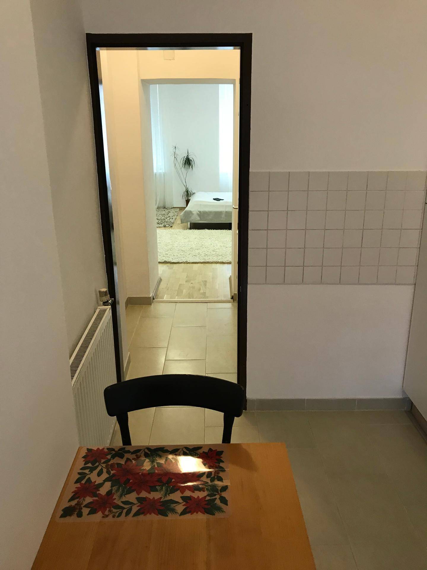 Blick durch einen Flur in ein Schlafzimmer, mit einem kleinen Tisch im Vordergrund des Raumes.