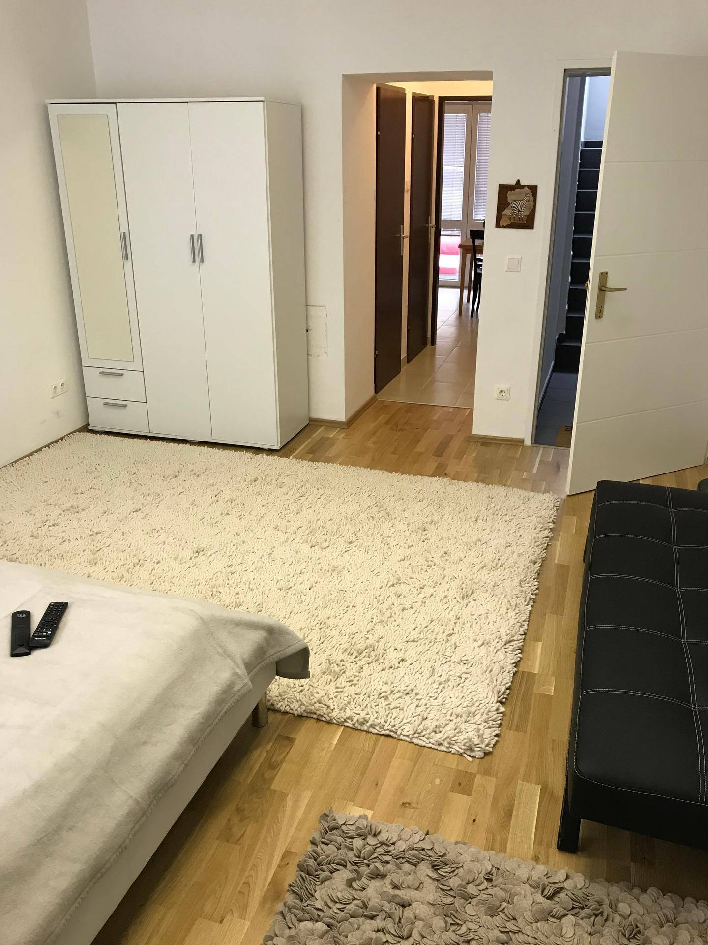 Geräumiger Innenraum mit Teppich, weißem Kleiderschrank und Zugang zu Flur und Treppe.