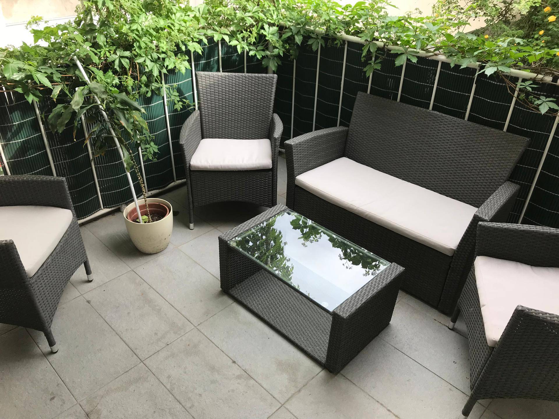 Attraktive Terrasse mit Rattan-Sitzgruppe und viel Grün, perfekt für sonnige Sommertage.
