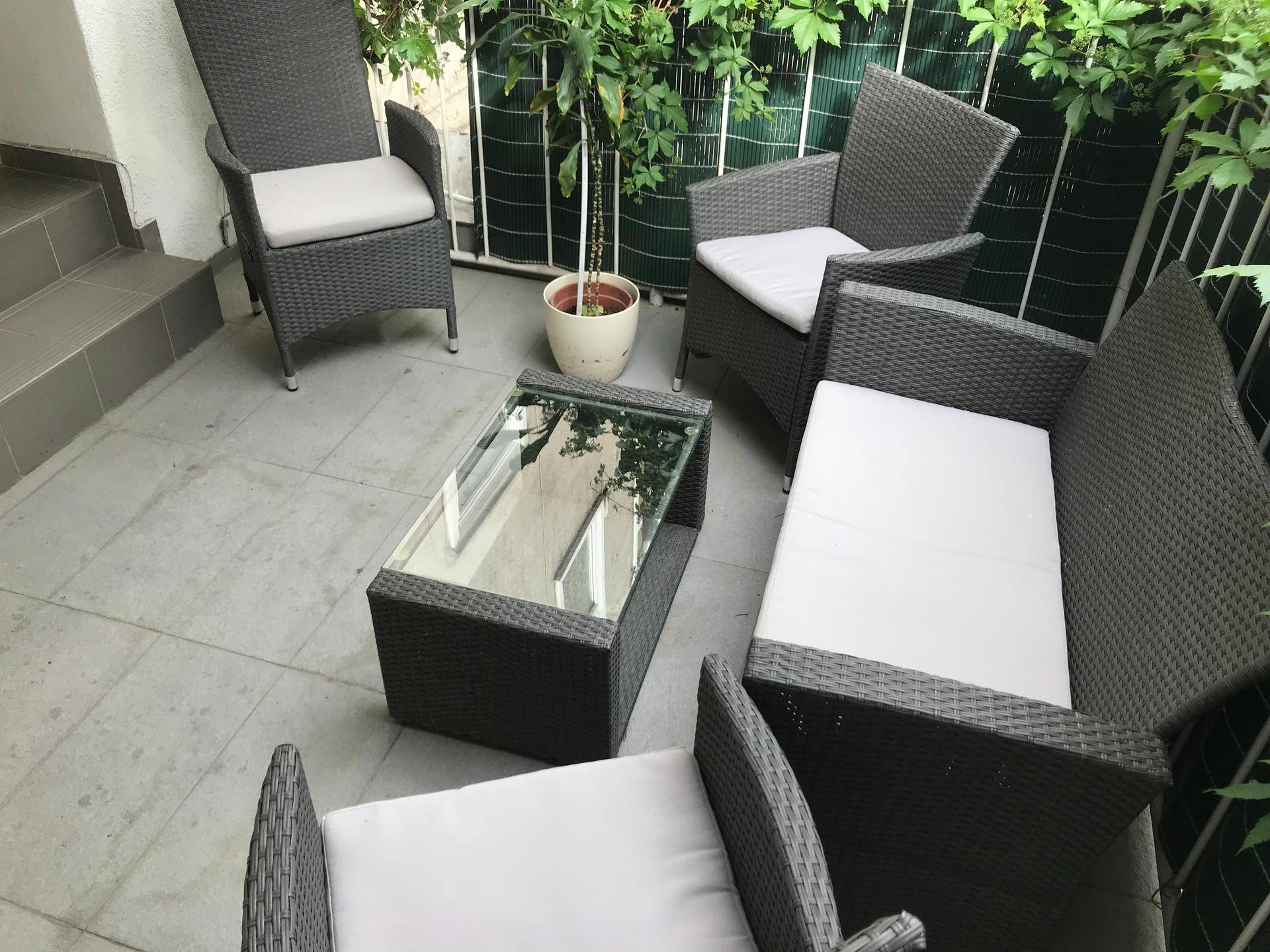 Gemütliche Terrasse mit Rattanmöbeln und üppiger Begrünung, ideal zum Entspannen im Freien.