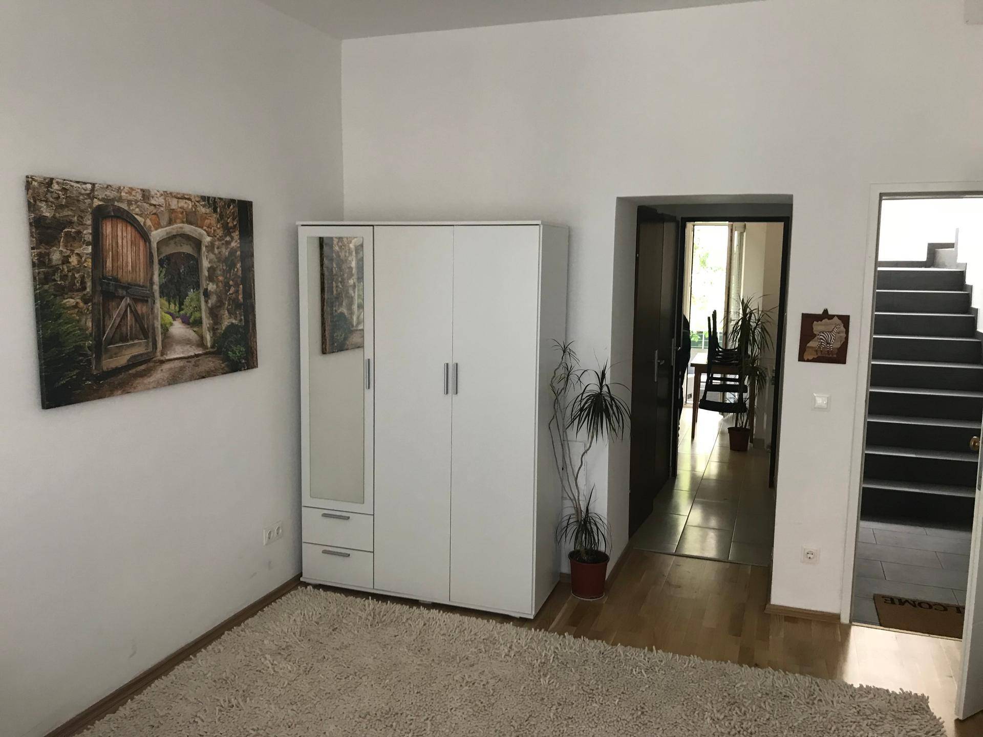 Heller Innenraum mit weißem Kleiderschrank und Blick auf den Flur und die Treppe.