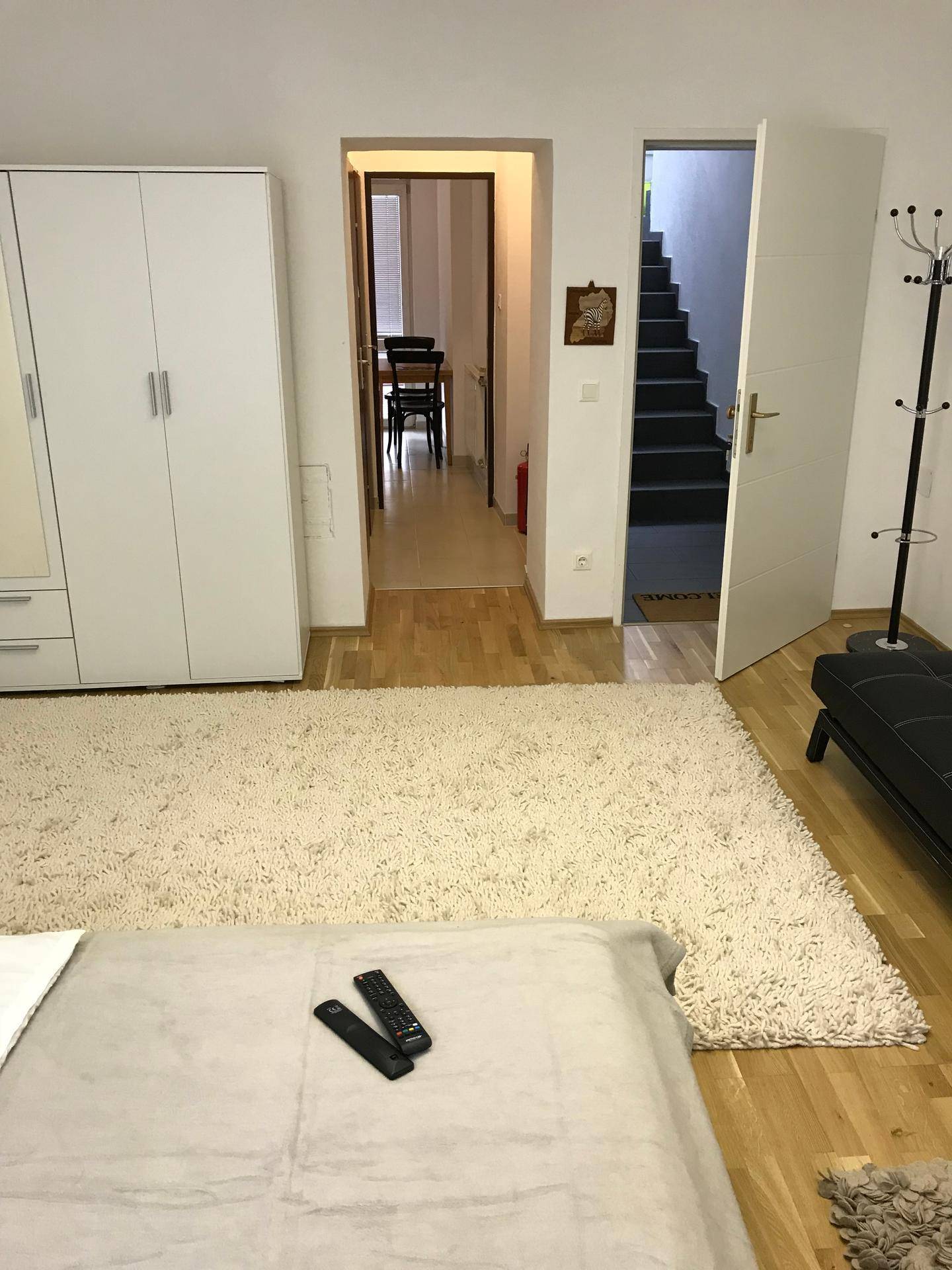 Innenansicht eines Raumes mit Blick auf einen Flur und eine Treppe, mit Teppichboden und Holzboden.