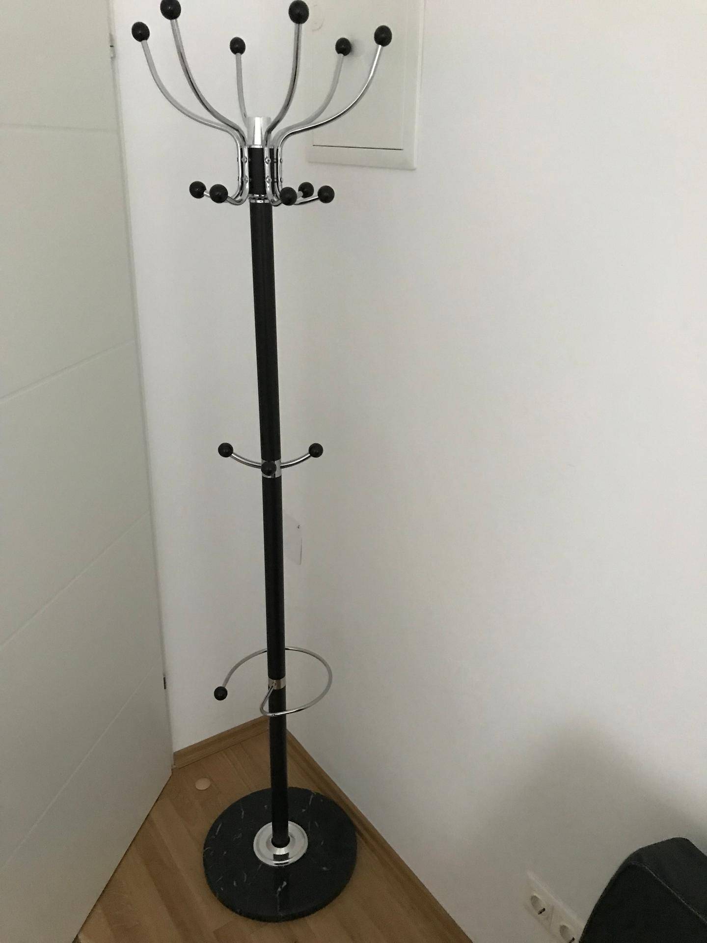 Moderner Garderobenständer mit vielen Haken in einer Ecke des Flurs, praktisch und stilvoll.