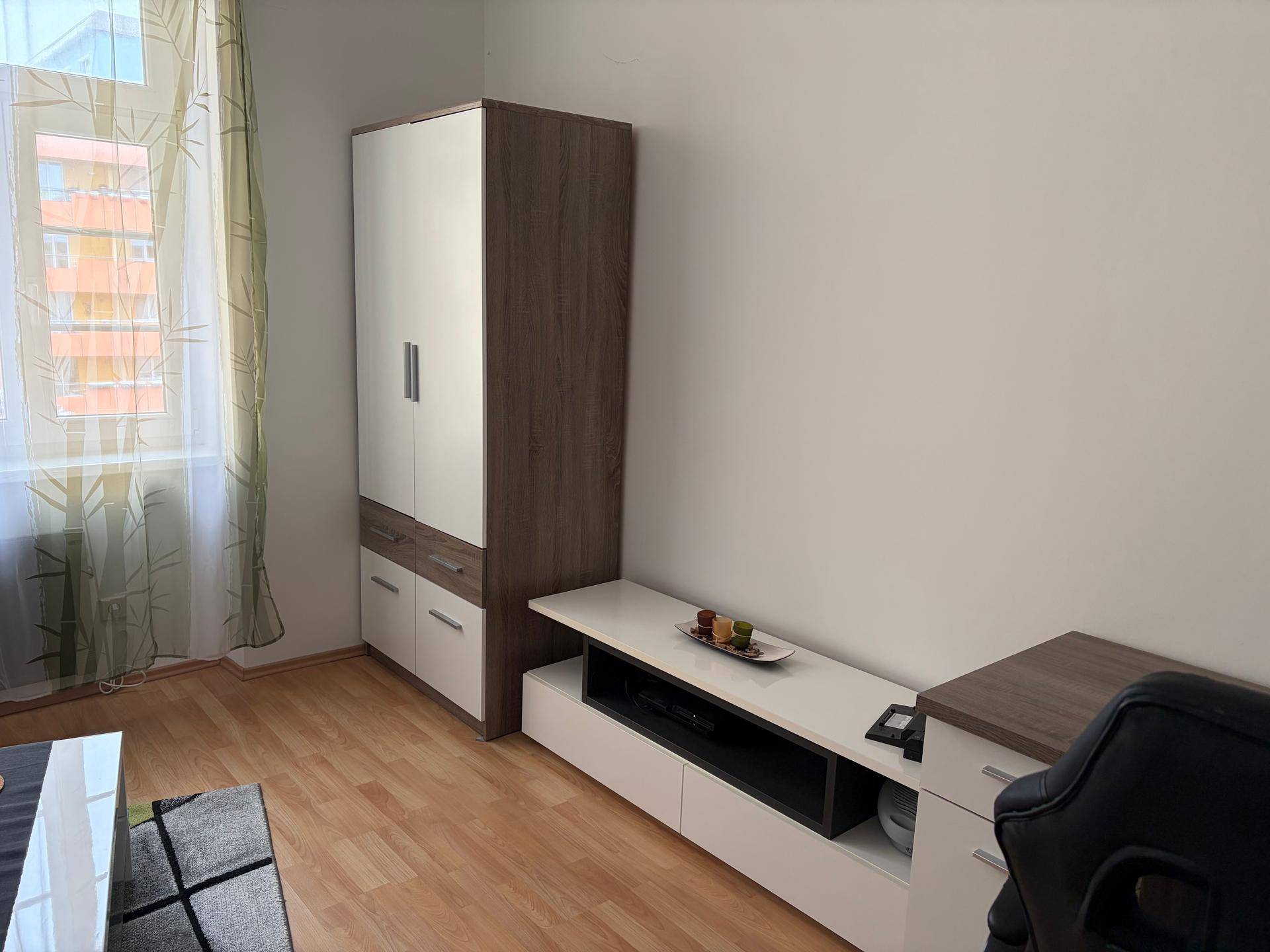 Wohnzimmerbereich mit Schrank, TV-Möbeln und Blick aus dem Fenster.