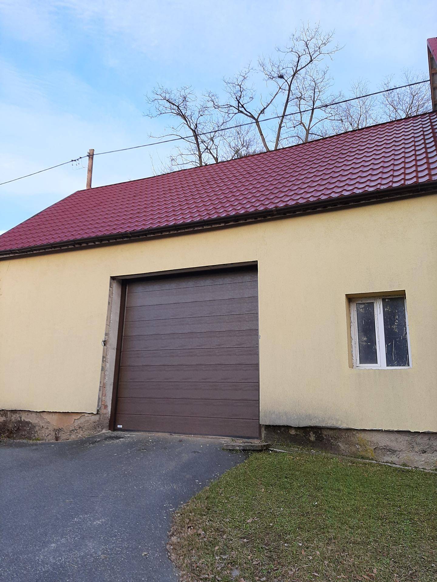 Nahaufnahme des großen braunen Garagentors am gelben Gebäude mit rotem Dach.