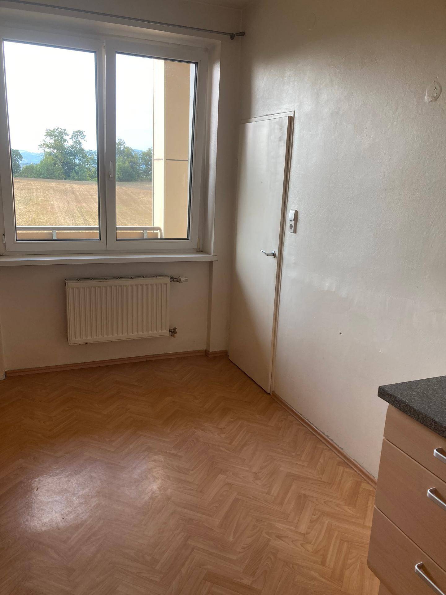 Heller Küchenbereich mit Fenster, Heizkörper und Blick auf die umliegende Landschaft.