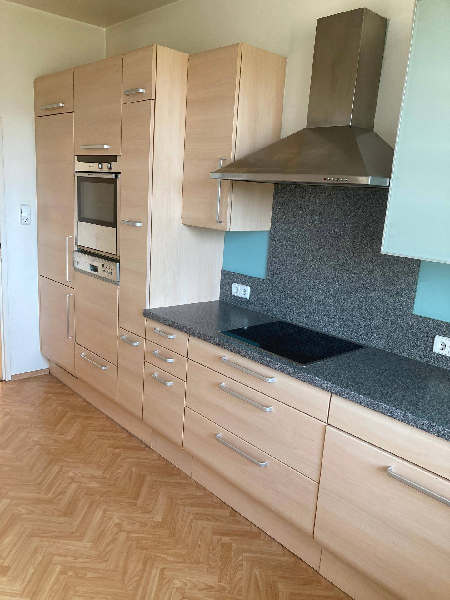 Funktionale Einbauküche mit integriertem Backofen, Dunstabzugshaube und Holzoptik.