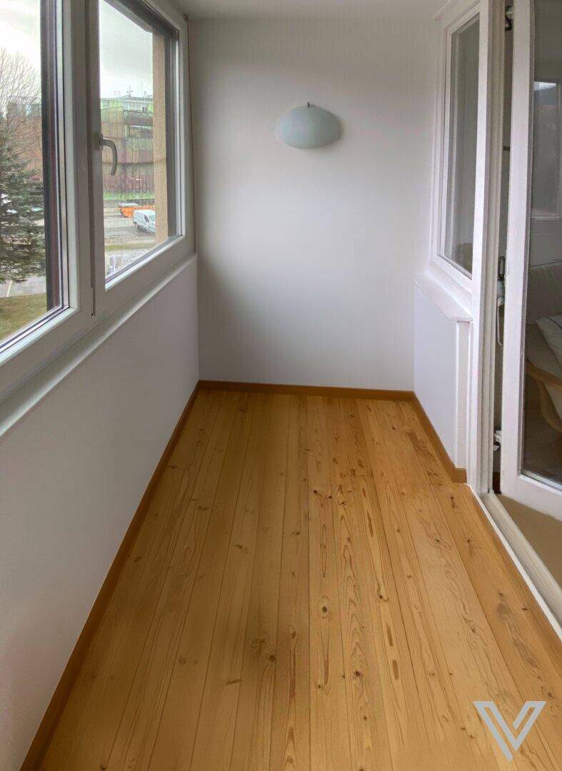 Helle Loggia mit Holzplankenboden und großen Fenstern, ideal für entspannte Stunden im Freien.
