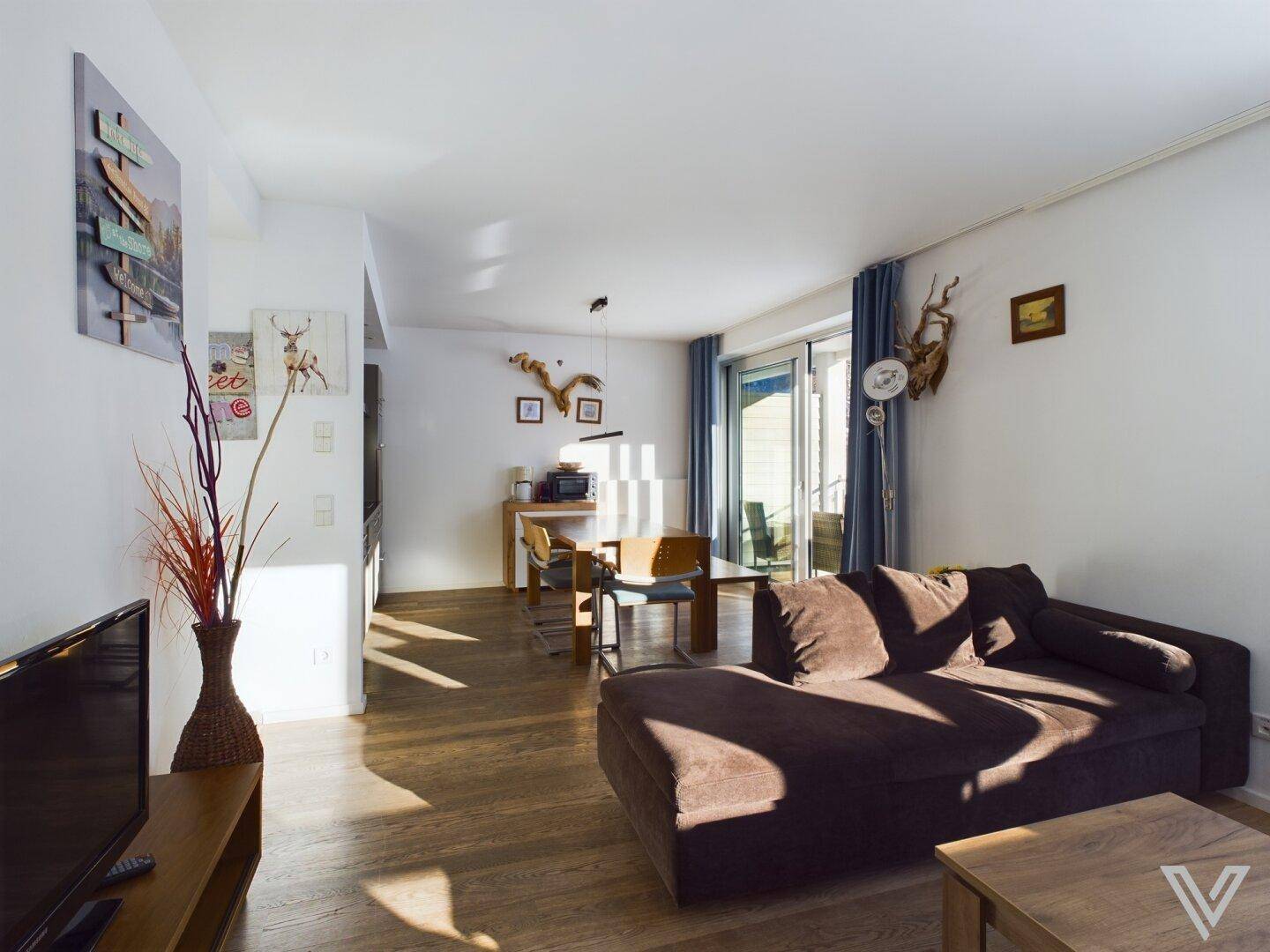 Offener Wohn- und Essbereich mit Holzboden und Zugang zum Balkon, hell und einladend gestaltet.