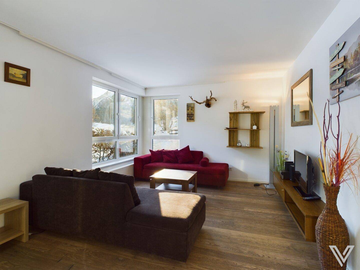 Helles Wohnzimmer mit bequemen Sofas, Holzboden und moderner Dekoration, bietet viel Tageslicht.
