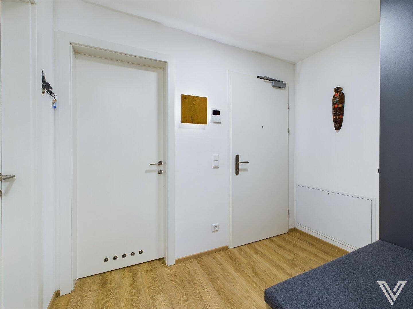 Heller Flur mit Holzboden und weißen Türen, modern und einladend gestaltet.