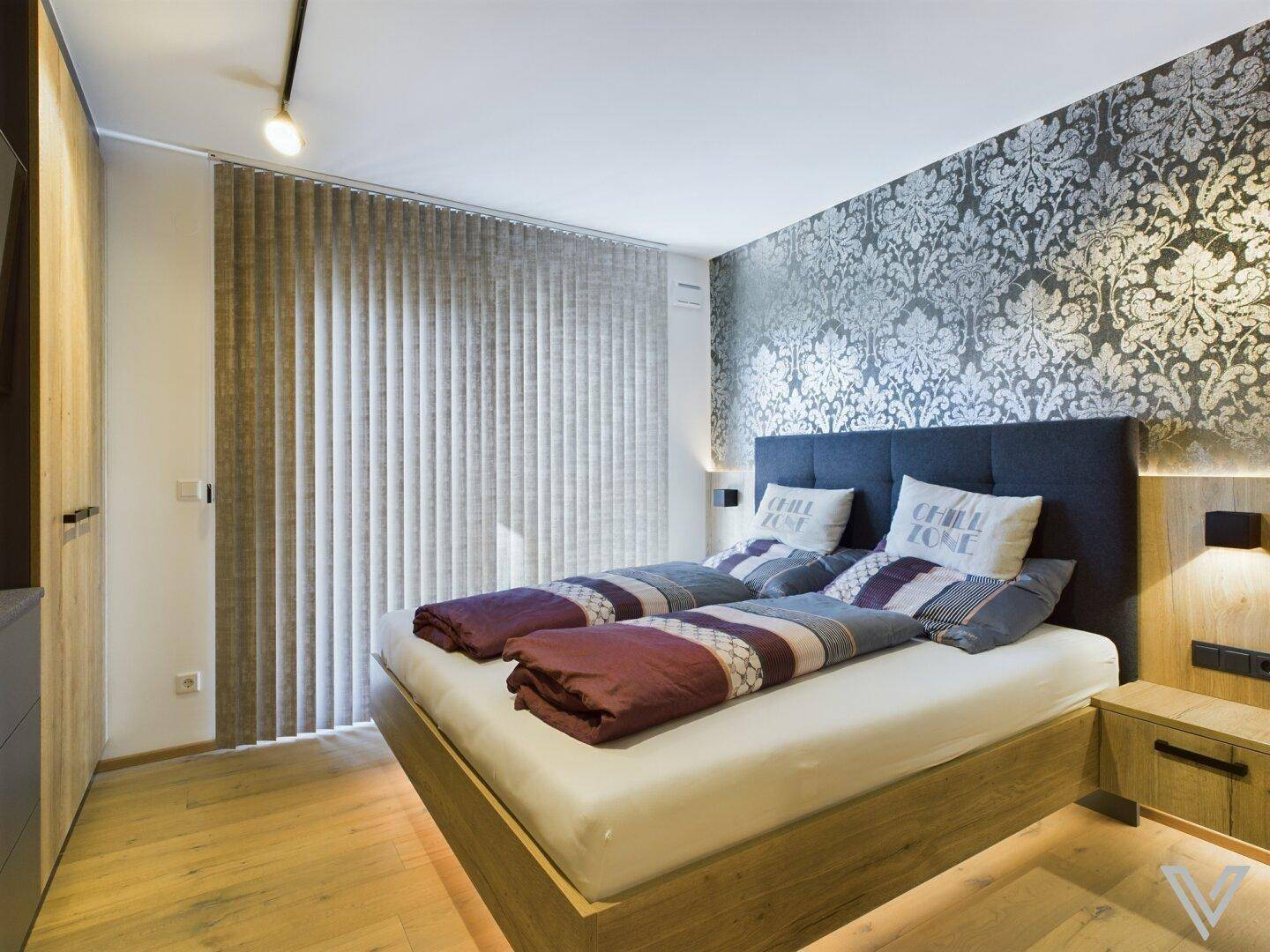 Schlafzimmer mit stilvoller Wandgestaltung, Holzboden und Zugang zum Balkon.