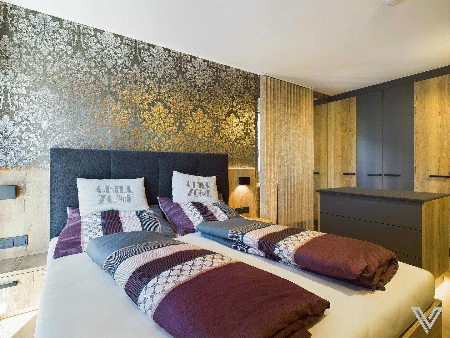 Schlafzimmer mit Doppelbett, gemusterter Tapete und Holzboden in modernem Stil.