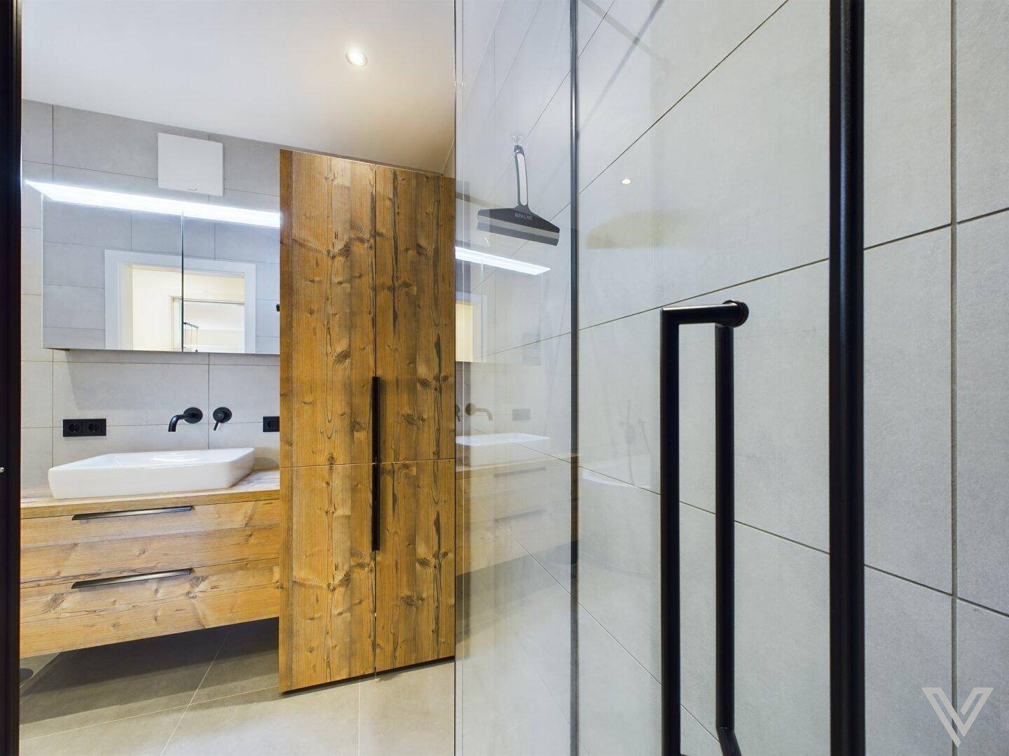 Modernes Badezimmer mit begehbarer Dusche, Holzwaschtisch und hellen Fliesen.