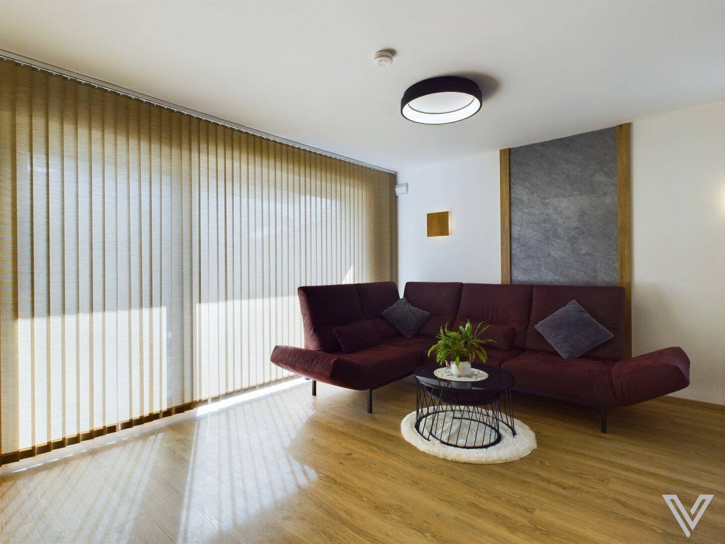 Lichtdurchfluteter Wohnbereich mit moderner Couch, stilvoller Wandgestaltung und Holzboden.
