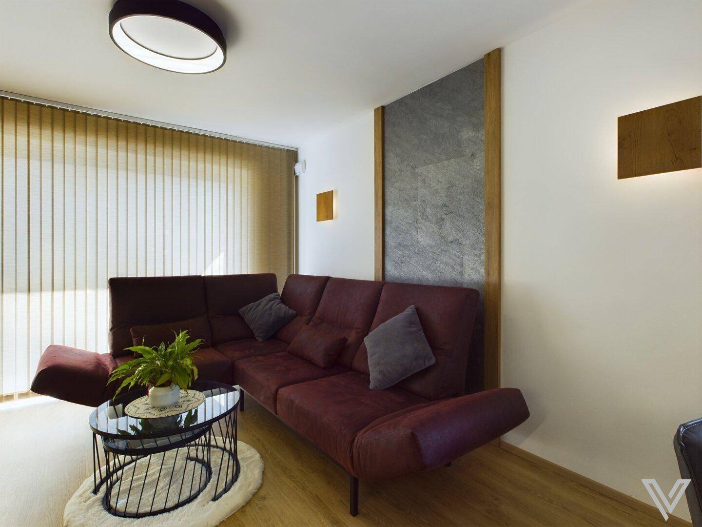Gemütliche Sitzecke im Wohnzimmer mit moderner Couch, indirekter Beleuchtung und Holzboden.
