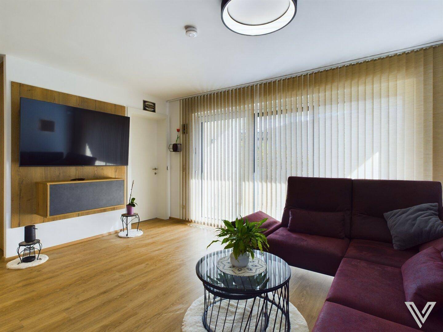 Wohnzimmer mit großer Fensterfront, bequemer Couch und modernem Design mit Holzboden.