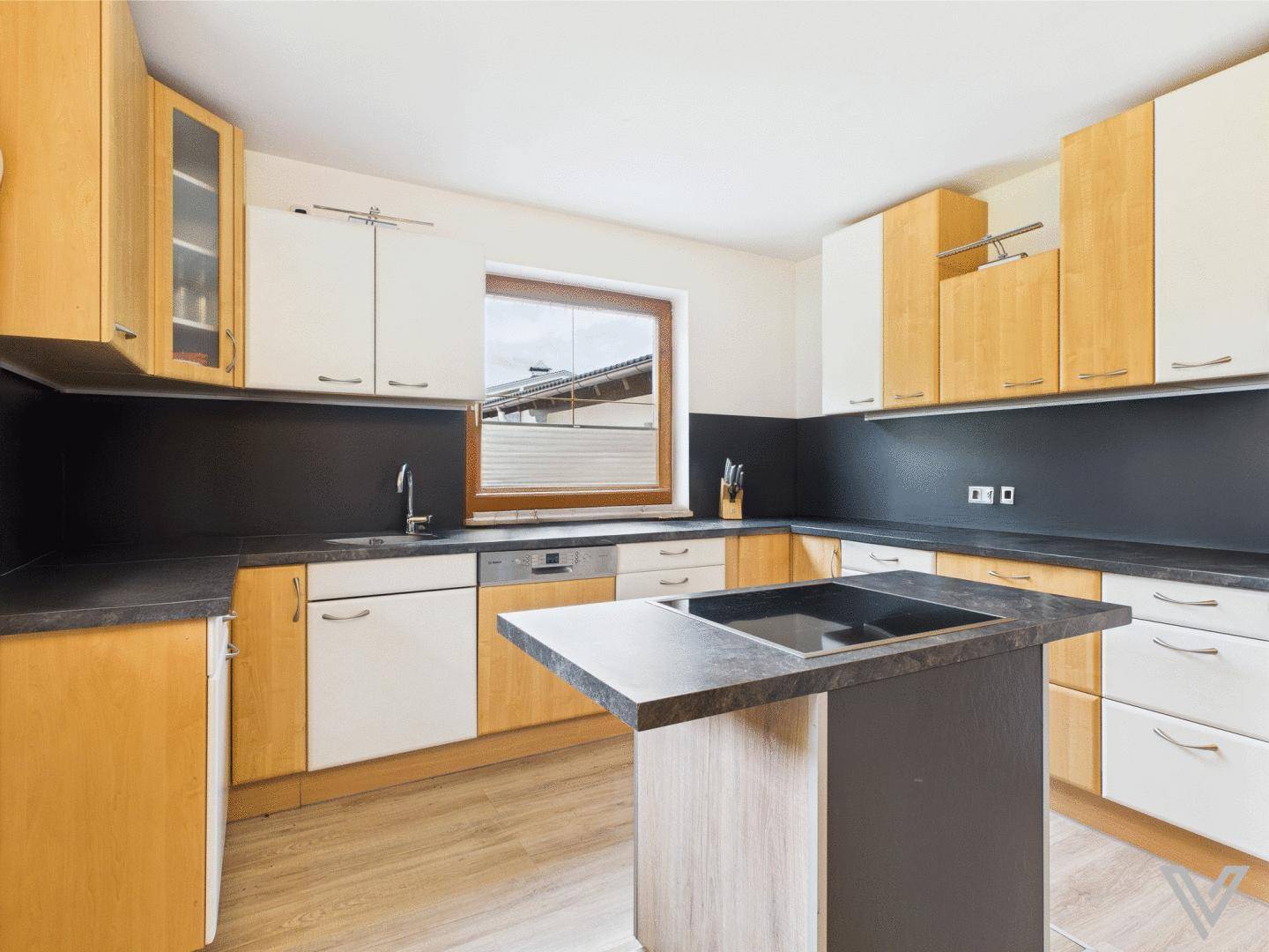Moderne Küche mit Holz- und weißen Schränken, dunkler Arbeitsplatte und Kochinsel.