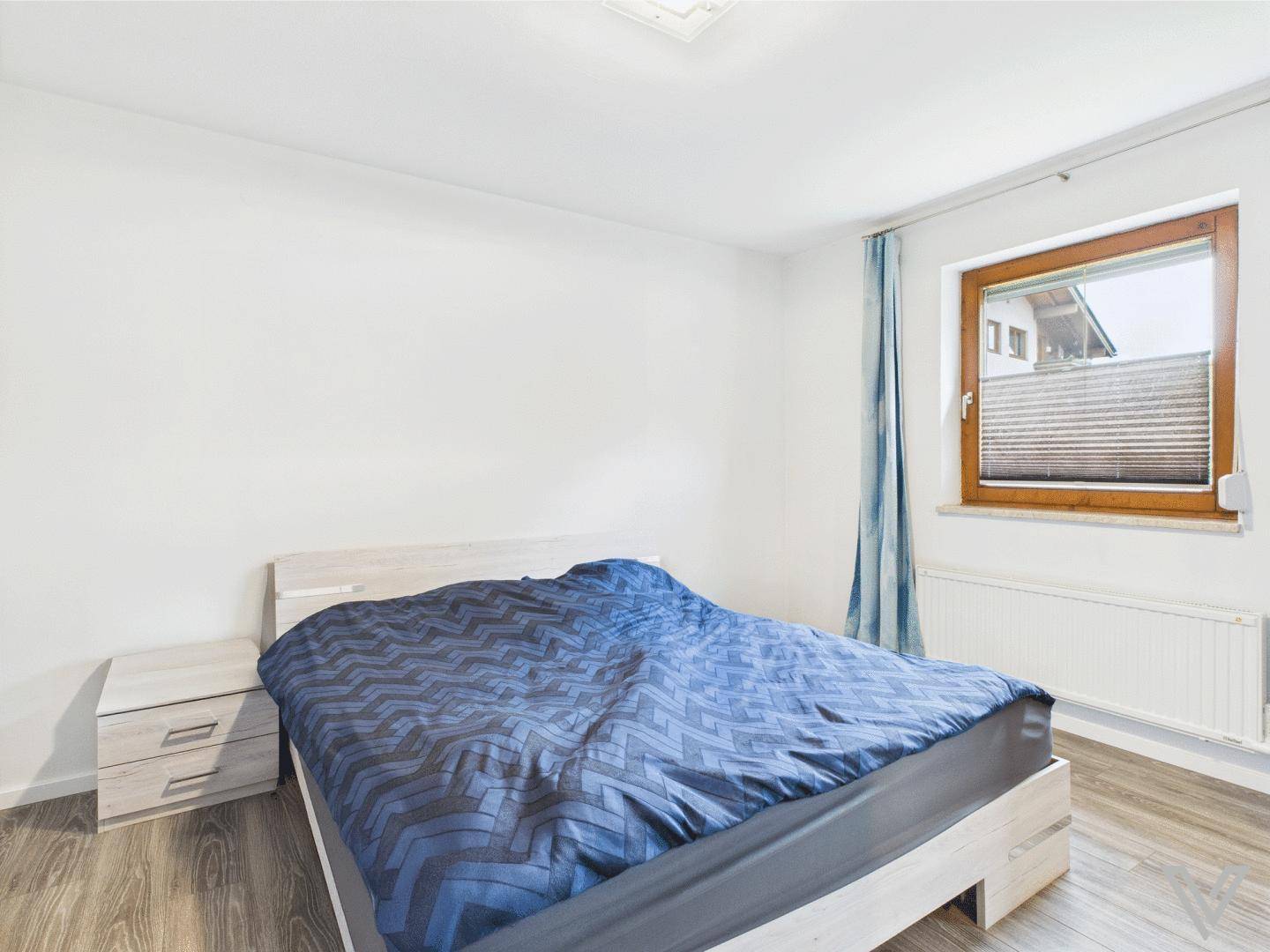 Schlafzimmer mit Doppelbett, Nachttischen und Fenster mit Blick nach draußen.