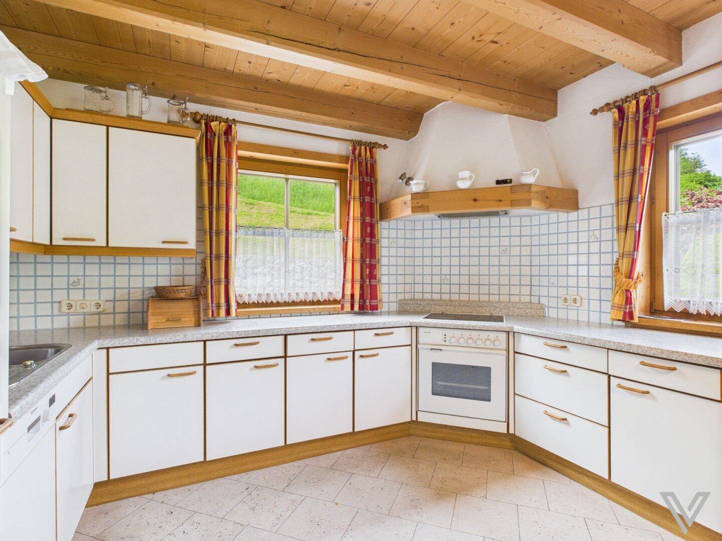Traditionelle Küche mit weißen Schränken, Fliesenrückwand und Blick ins Grüne.