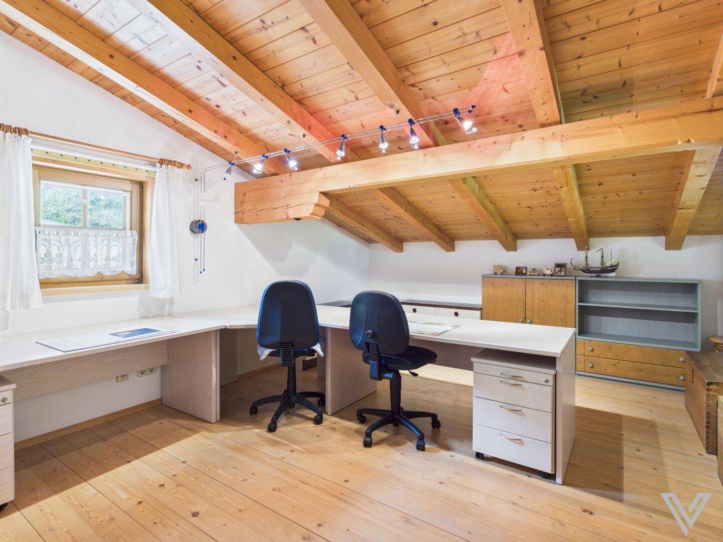 Geräumiges Büro mit zwei Arbeitsplätzen, Holzbalkendecke und Blick ins Grüne.
