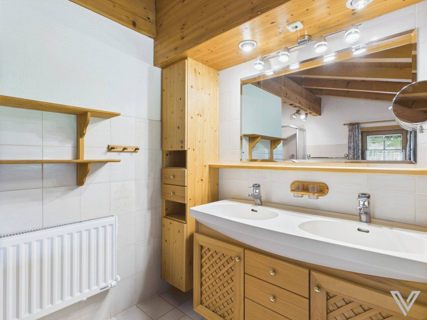 Badezimmer mit Doppelwaschbecken, großem Spiegel und Holzbalkendecke.