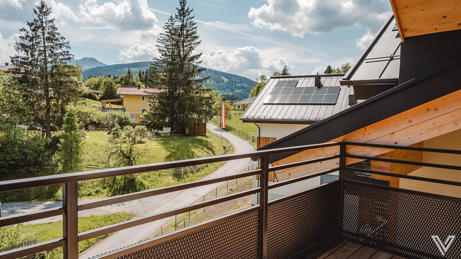 Balkon mit Metallgeländer und weitem Blick auf die umliegende Berglandschaft und Solaranlage.