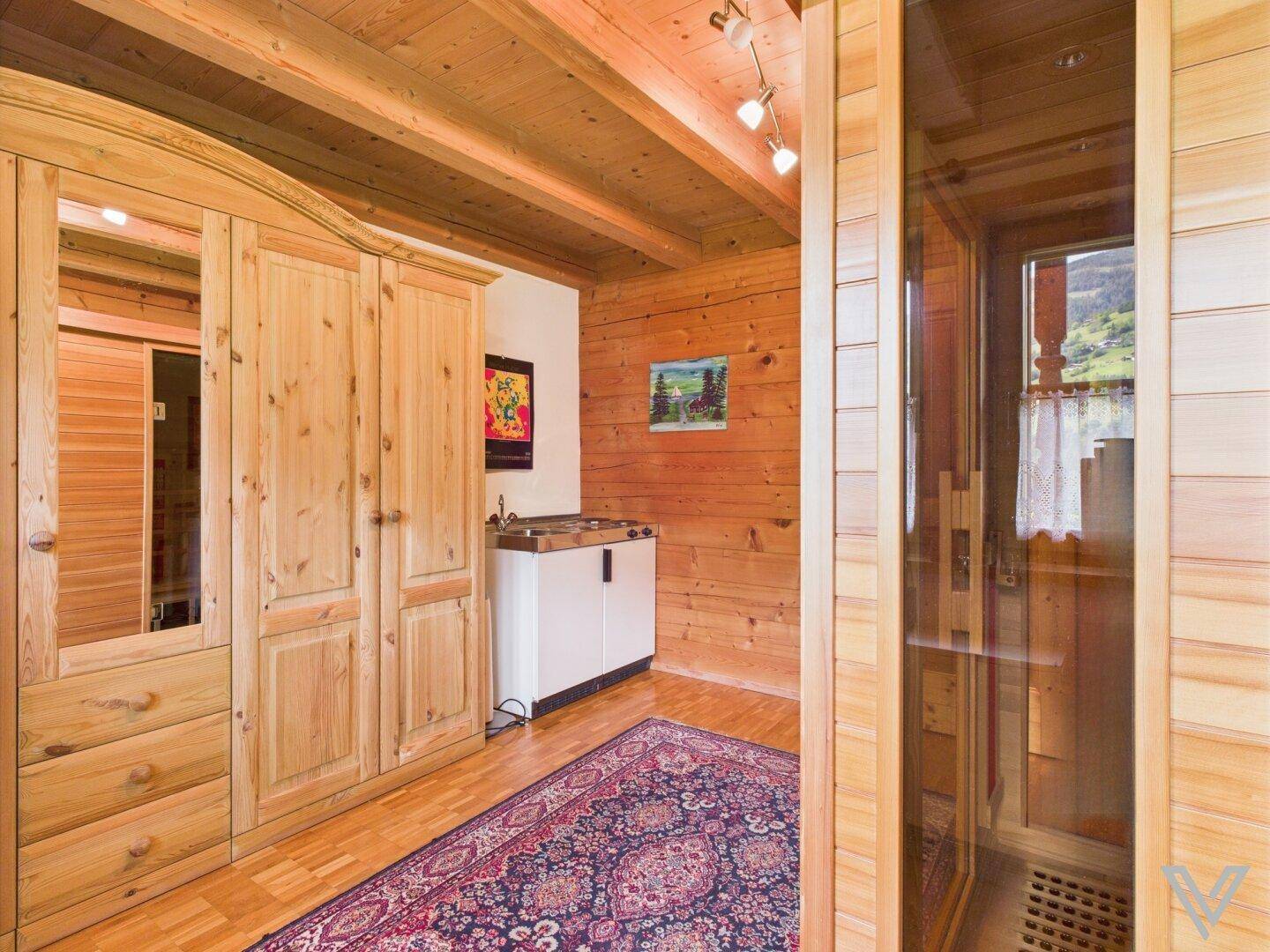 Bereich mit Sauna, Holzschränken und Teppich, passend zum rustikalen Stil des Hauses.