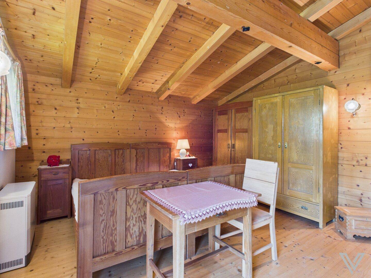 Schlafzimmer mit Holzbalkendecke, Einzelbetten und traditionellen Holzschränken.
