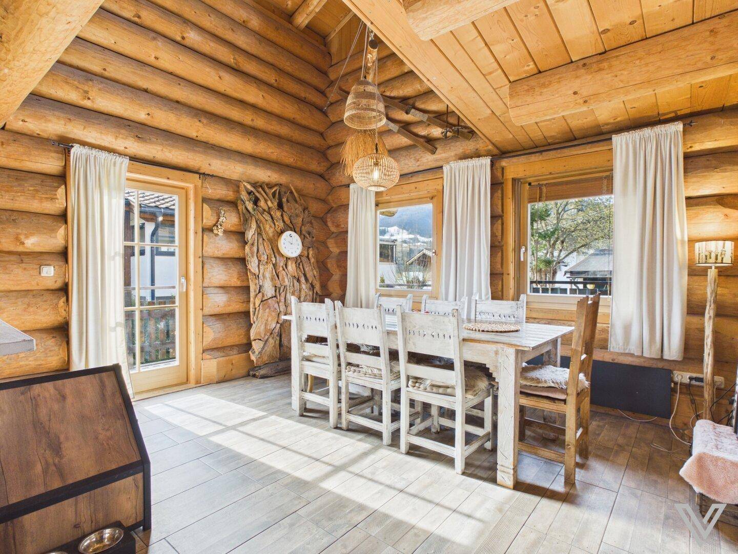 Heller Essbereich mit Holztisch, Stühlen und Zugang zur Außenterrasse mit Bergblick.