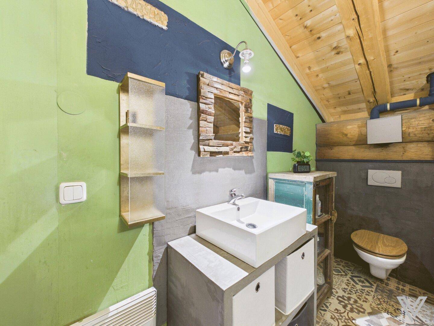 Modernes Badezimmer mit Waschtisch, WC und farbigen Wänden unter der Dachschräge.