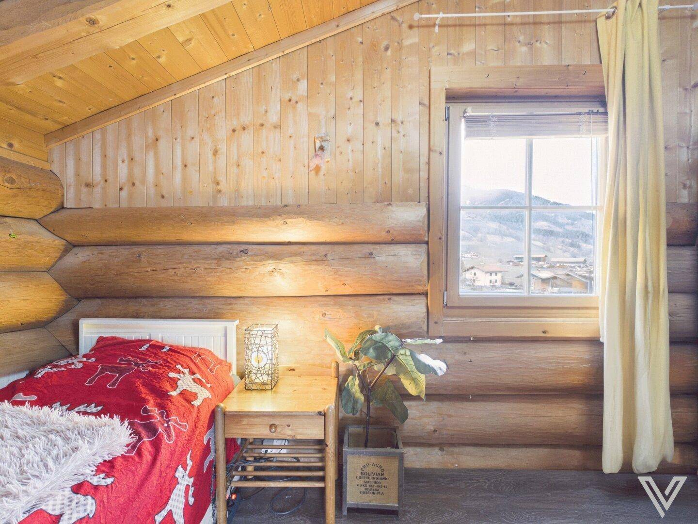 Gemütliches Schlafzimmer im Dachgeschoss mit Holzwänden, Einzelbett und Fenster.