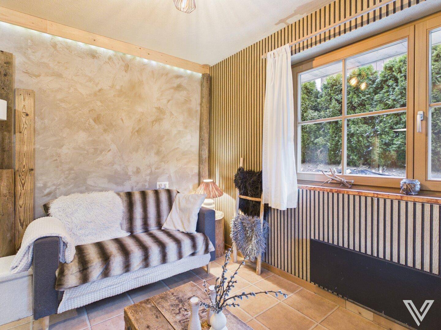 Gemütliches Wohnzimmer mit Sofa, Holztisch und vertikalen Holzpaneelen an der Wand.