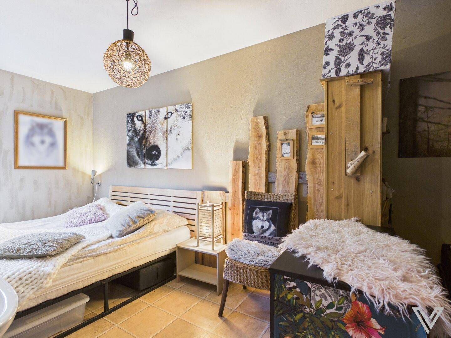 Schlafzimmer mit Doppelbett, rustikalen Holzakzenten und Wandbildern im alpinen Stil.