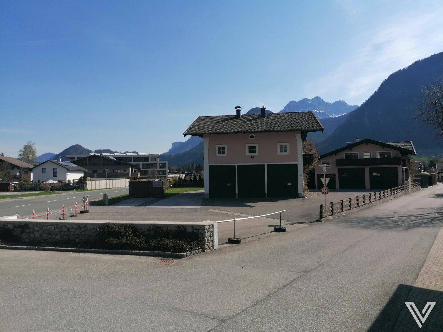 Gebäude mit Garagentoren und Bergpanorama im Hintergrund an einem sonnigen Tag.
